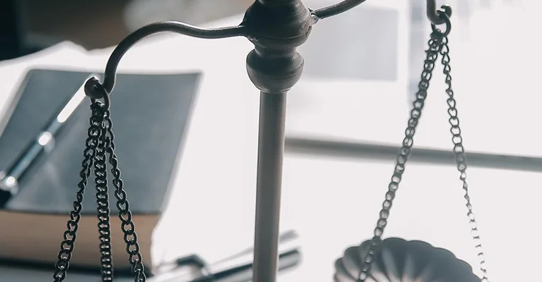 Close-up of legal scales on a desk with law books and documents in the background
