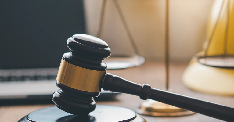 Judge's gavel with yellow hard hat and scales of justice on a desk, symbolizing workplace injury law.