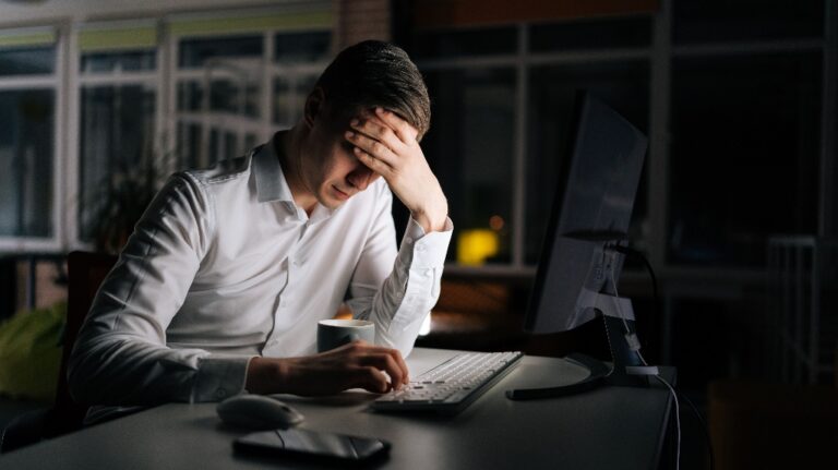Tired male office worker working late at night