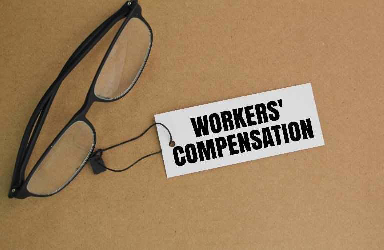 glasses and a paper tag with the word workers' compensation