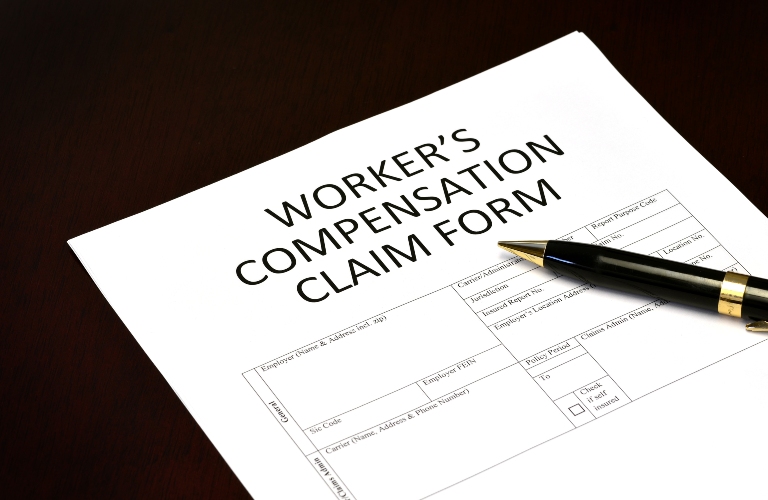 Worker's compensation claim form application with pen on desk